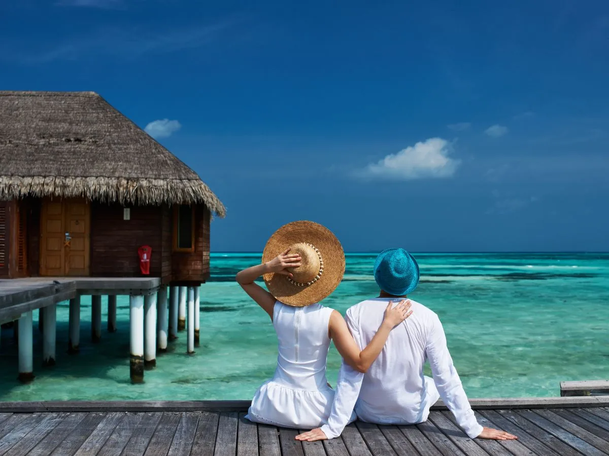 Coppia in viaggio di nozze davanti a una water villa alle Maldive